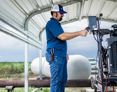 A man checks a propane device on a farm.