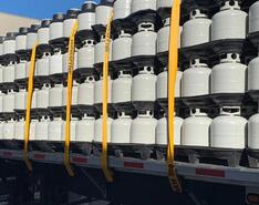 A truck transports a large load of white propane cylinders