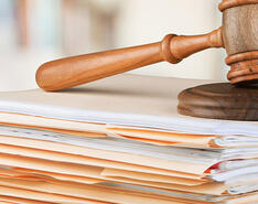 A gavel resting on top of many folders stacked on each other