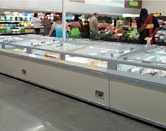 Customers shop in a frozen food section.