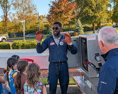 A Suburban Propane driver stand at the back of a propane bobtail and speaks to a Girl Scout troop and their moms about driving at the Trucks Are for Girls event
