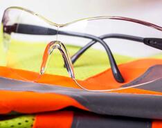 PPE glasses sitting on top of an orange, yellow and gray PPE vest