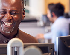 A customer service representative smiles while using a headset.