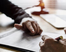Hands mull over a legal document, showcasing the importance of indemnification clauses