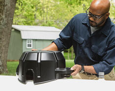 A man works with a propane tank monitoring device