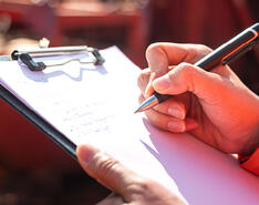 A person holds a clipboard and is assumed to be going through a list.