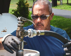 Man in sunglasses refills propane tank