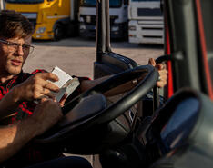 A man in glasses checks a log with a truck driver sitting behind the wheel of a truck to demonstrate employee retention in the propane industry