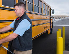 A man fills a school bus at with an autogas fueling dispenser.