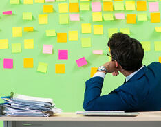 A man looking at a post-it filled wall
