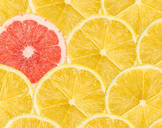 A single red grapefruit slice standing out among a crowd of yellow lemon slices