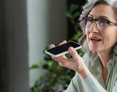 A woman uses speakerphone to talk on her smart phone