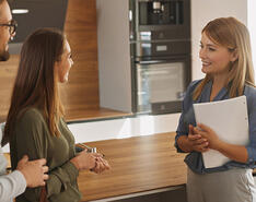 A picture depicting a sales representative speaking to two clients in a clean showroom.