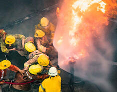 Firefighters are pictured using fire hoses to fight off a growing flame.