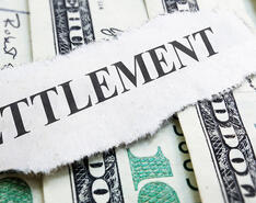 The word "settlement" is pictured against a stack of money.
