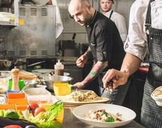 Chefs prepare a colorful dish in a restaurant, excercising the same care needed for succession planning