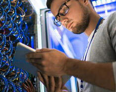 A man looks down at an electronic tablet.