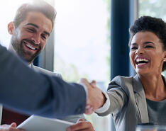 A businesswomen reaches out to shake hands while smiling, symbolizing a healthy fractional relationship.