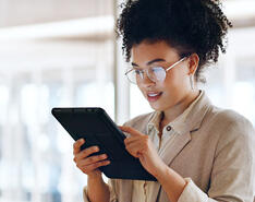 A woman looks at a tablet in an office setting.