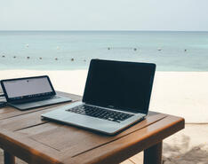 A picture of a laptop is featured with a backdrop of a beach.