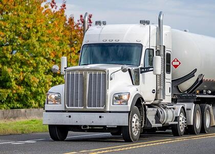 A white propane hauler is depicted driving down the road.