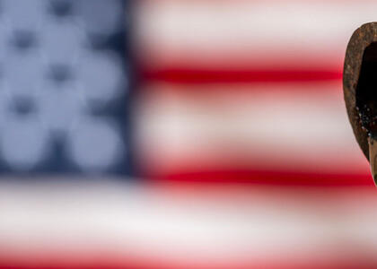 A pipeline drips propane supply oil against the backdrop of an American flag.