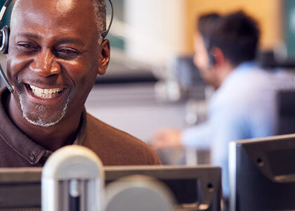 A customer service representative smiles while using a headset.