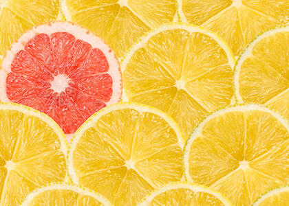 A single red grapefruit slice standing out among a crowd of yellow lemon slices