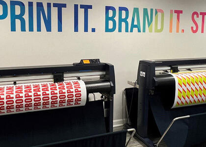 A printing machine is displayed printing off signs and marketing material.