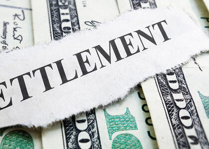 The word "settlement" is pictured against a stack of money.