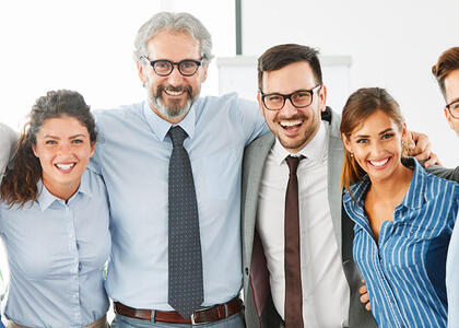 Business employees stand, smiling, symbolizing a successful M&A transaction.